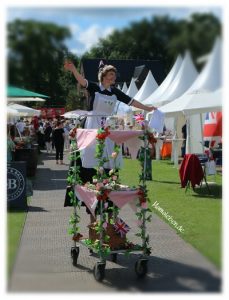 englische Frau auf Stelzen mit Teewagen