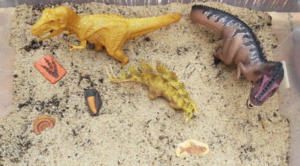 Dinosaurier mit Fossilien für Kinder in einer Sandkiste